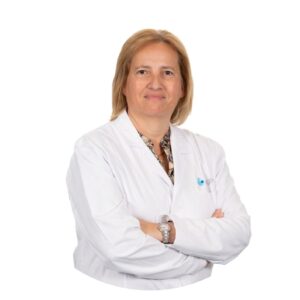 La dottoressa Ana Teresa Almeida Santos, PhD, della clinica Eugin di Coimbra, indossa un camice bianco e sta con le braccia incrociate davanti a uno sfondo bianco.