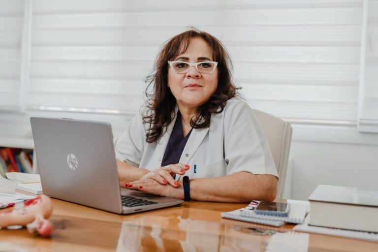La Dottoressa Serap Kagan, specialista in fertilità del Cyprus IVF Hospital, seduta alla scrivania del suo ufficio con un laptop HP, documenti medici e libri, pronta ad assistere i pazienti nei trattamenti di IVF e donazione di ovuli.